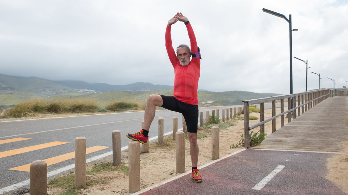 Elderly man in sportswear stretches on a scenic path in Portugal, promoting fitness and healthy lifestyle.